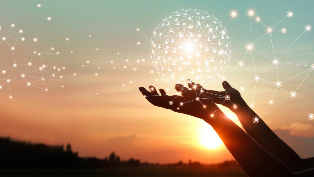 Man's arms outstretched appearing to hold a digital sphere at sunset